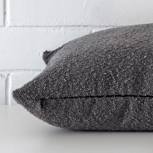 Side edge of square cushion. The boucle material and dark grey colour can be seen from this lateral viewpoint.