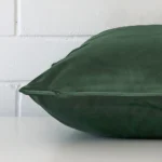 The edge of this velvet square cushion in dark sage is shown. The shot shows the TYPE design and the front and rear panels.