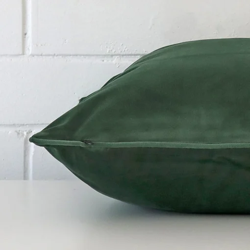The edge of this velvet square cushion in dark sage is shown. The shot shows the TYPE design and the front and rear panels.