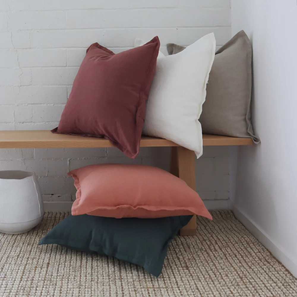 Five decorative cushions arranged in a row and in a stack of a corner scene.