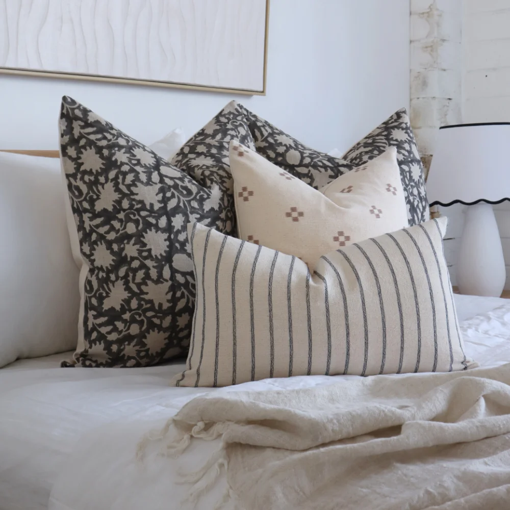 Four designer cushions are layered in a stylish arrangement.
