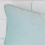 The corner of this velvet rectangle cushion cover is shown close up. The duck egg colour is shown in greater detail.