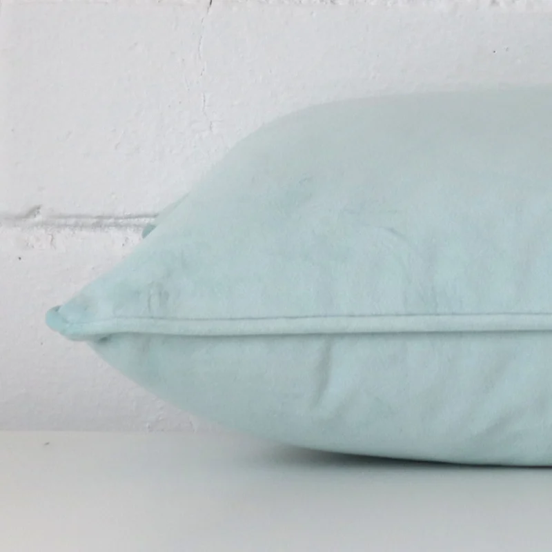 Side angle shot of velvet rectangle cushion cover. It shows a duck egg hue.