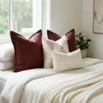 Elle cushions on bed with deep burgundy, soft floral and fine stripe patterns.