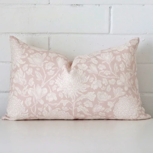 Close up view showing a corner of this floral linen cushion in a rectangle size and with light pink colouring.
