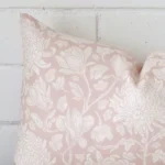 Zoomed in visual of linen rectangle cushion cover in light pink. The intricacies of its floral design are visible.