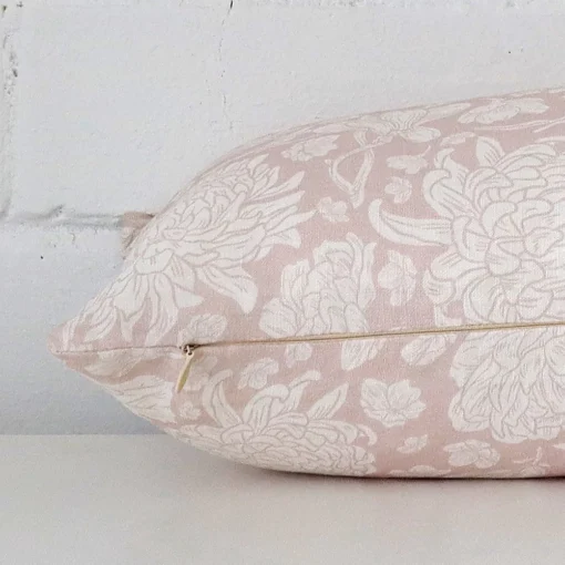 A sideways perspective of this floral linen cushion. The positioning shows the border of the rectangle shape and the light pink colour.