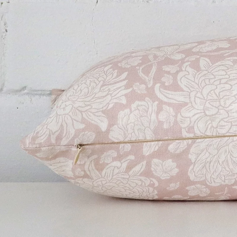 A sideways perspective of this floral linen cushion. The positioning shows the border of the rectangle shape and the light pink colour.