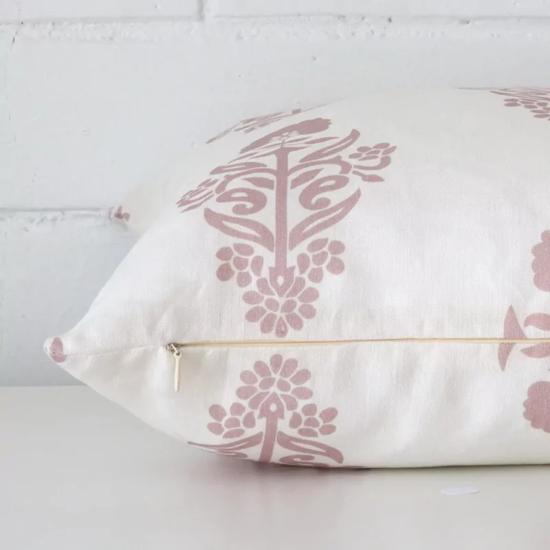Pink patterned cushion cover laying sideways against brick wall. The square size and linen material are shown highlighting the seams.