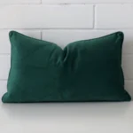 Bold rectangle emerald green cushion positioned in front of white brickwork. It is made from velvet fabric.