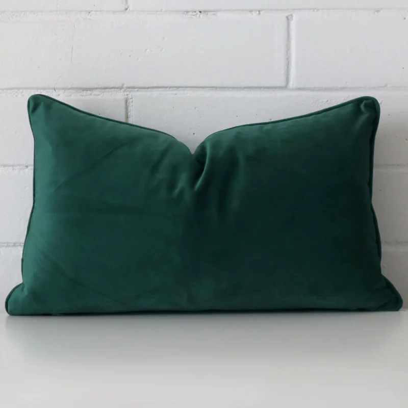 emerald-green-rectangular-velvet-cushion-cover-30cm-x-50cm-sc499-30 Bold rectangle emerald green cushion positioned in front of white brickwork. It is made from velvet fabric.