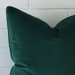 Corner section image showing features of square emerald green cushion. It is made from velvet fabric.