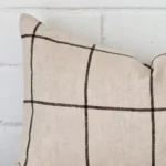 Corner section image showing features of rectangle cushion that has a check motif on its linen fabric.