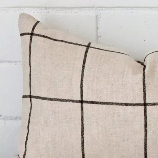 Corner section image showing features of rectangle cushion that has a check motif on its linen fabric.