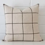 Very close photo of check cushion. The shot shows the linen material and square dimensions with more clarity.