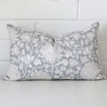 Light blue linen cushion cover features prominently against a white wall. It is a rectangle design and has a floral decorative finish.