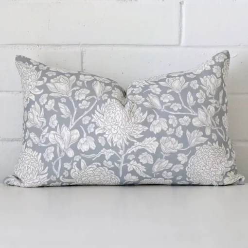 Light blue linen cushion cover features prominently against a white wall. It is a rectangle design and has a floral decorative finish.