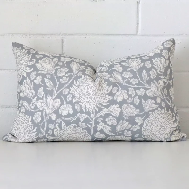 eva-linen-light-blue-floral-cushion-cover-rectangle-sc1009-30 Light blue linen cushion cover features prominently against a white wall. It is a rectangle design and has a floral decorative finish.