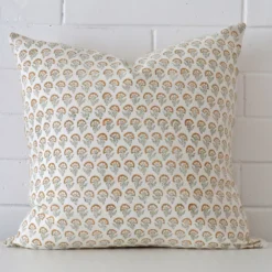 Designer cushion cover features prominently against a white wall. It is a square design and has a floral decorative finish.