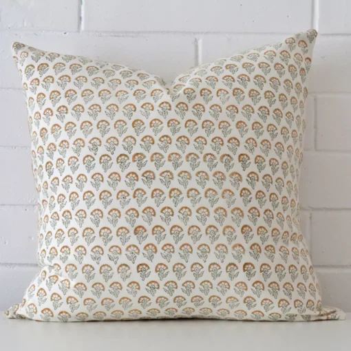 Designer cushion cover features prominently against a white wall. It is a square design and has a floral decorative finish.