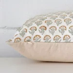 Floral cushion laid horizontally. This perspective shows the edge of the designer fabric and its square shape.