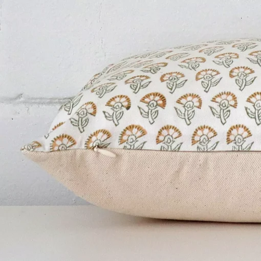 Floral cushion laid horizontally. This perspective shows the edge of the designer fabric and its square shape.