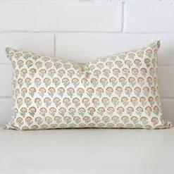 An attractive floral designer cushion in front of a white brick wall. It has a rectangle shape.