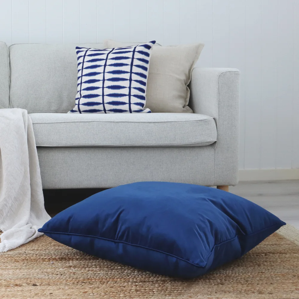 A floor cushion is placed on a rug in the middle of a room.