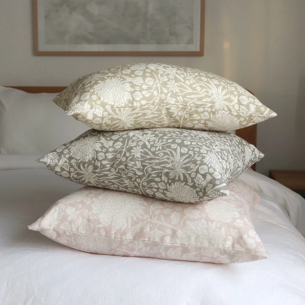Three floral cushions in several colours sit stacked on top of each other.