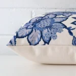 Floral cushion cover laying sideways against brick wall. The square size and linen material are shown highlighting the seams.