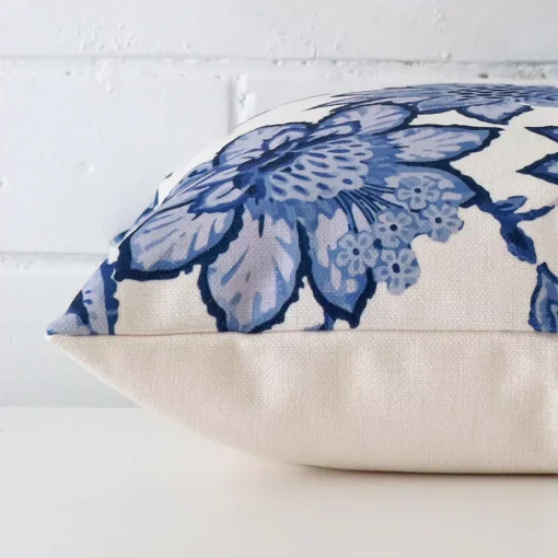 Floral cushion cover laying sideways against brick wall. The square size and linen material are shown highlighting the seams.
