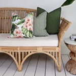 A set of 3 olive outdoor cushions on the corner of a rattan seat.