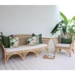 Outdoor sofa adorned with seven olive cushions snugly surrounded by lush greenery.