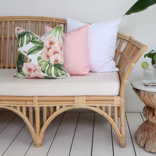 A floral pink outdoor couch cushion is paired perfectly with solid white and solid pink cushions.