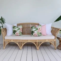 A set of five outdoor sofa cushions, including solid white, solid pink, and floral patterns, looks charming in a lounge.