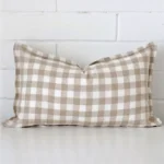 Gingham cushion cover sits against a white wall. It is constructed from a superior looking designer material and has rectangle dimensions.