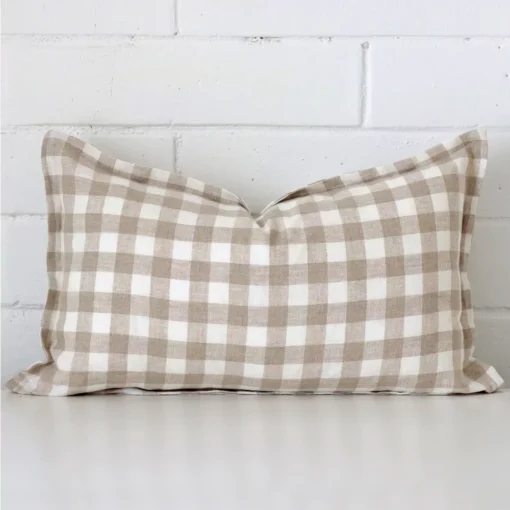 Gingham cushion cover sits against a white wall. It is constructed from a superior looking designer material and has rectangle dimensions.