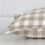 A sideways perspective of this gingham designer cushion. The positioning shows the border of the rectangle shape.