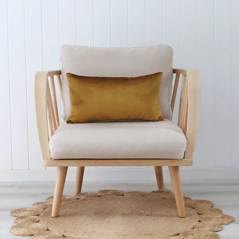 A gold cushion placed across a single chair with a wooden frame.