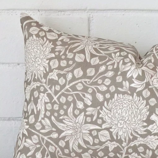 The corner of this linen rectangle cushion cover is shown close up. The floral design and grey colour is shown in greater detail.