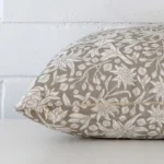 Close side shot of this grey linen cushion cover. The viewpoint shows how the square design and floral decorative finish meet along its edge.