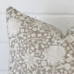 Close range image of grey floral cushion. The square size and linen material can be seen in detail.