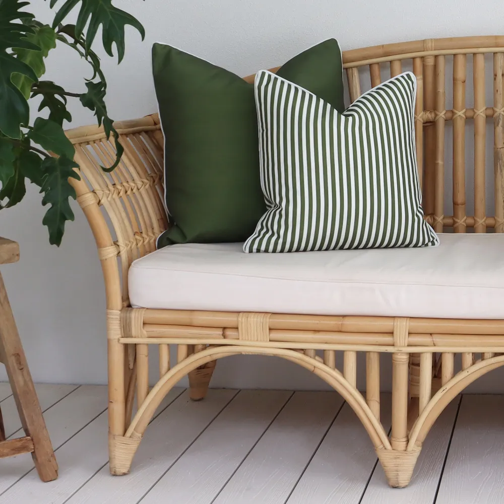 Two green outdoor cushions on a chair against a wall.