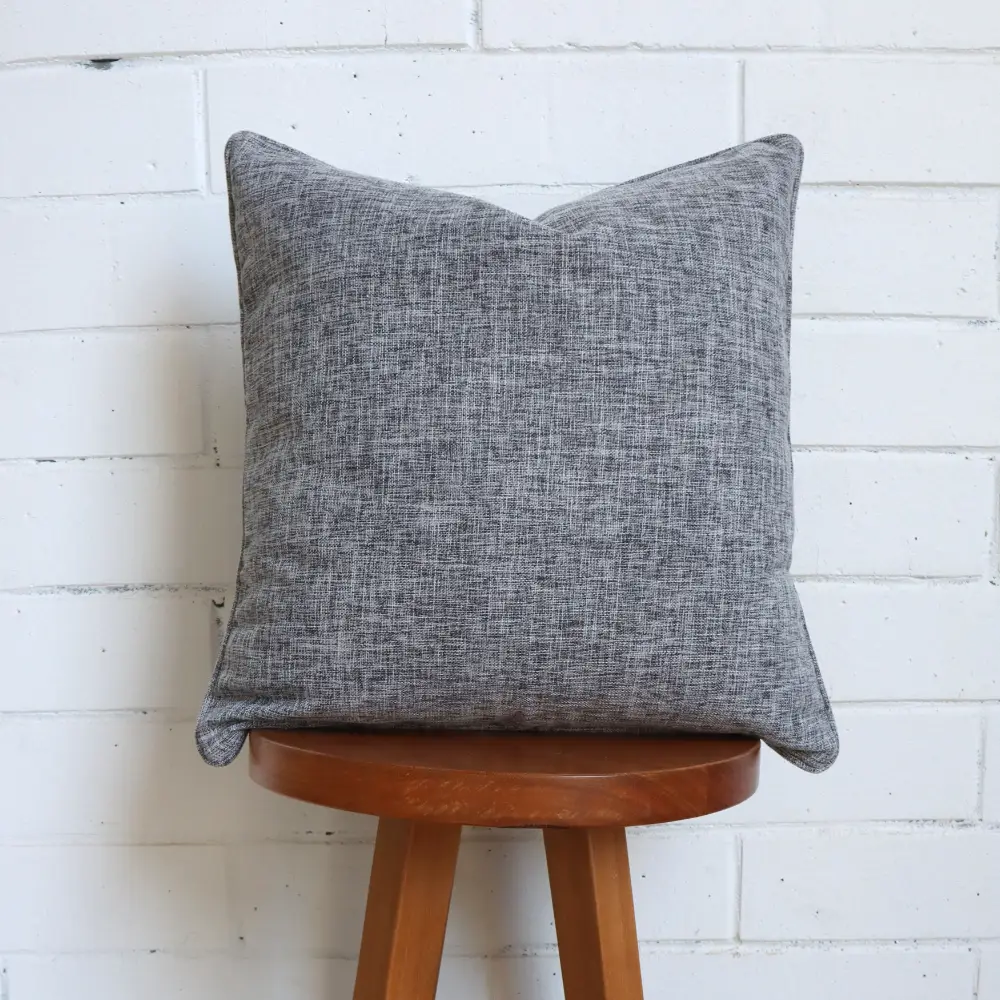 A grey cushion sits on top of a high stool made of wood.