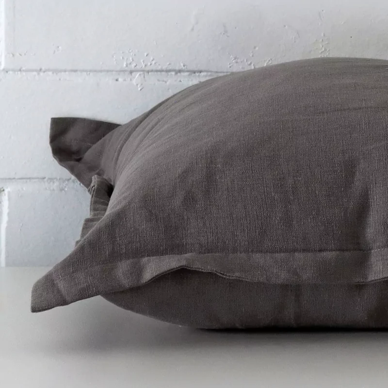 Side edge of linen square cushion. The linen material and grey colour can be seen from this lateral viewpoint.