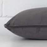 Velvet grey cushion laying on its side. It has a rectangle shape.