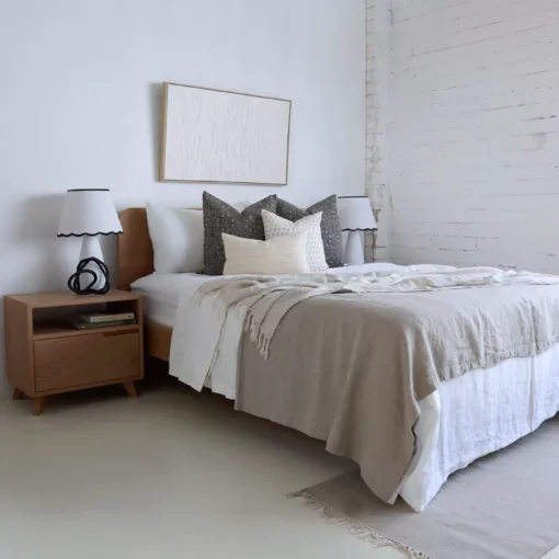 An airy white bedroom with 4 designer cushions from the Hali set sitting on a wooden bed.
