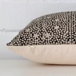 The edge of this designer square cushion is shown. The shot shows the front and rear panels.