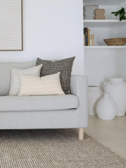 Designer sofa cushions set are arranged nicely on a light grey sofa in a living room.