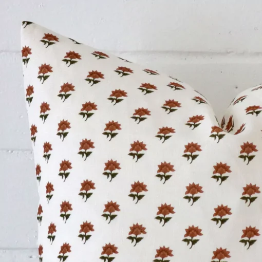 Macro shot showing the top left side of this square linen cushion. The terracotta hue and floral design is magnified.